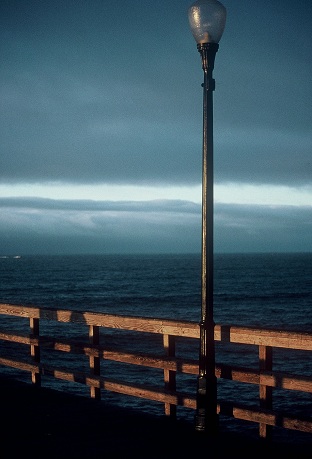 California pier with blue water of the Pacific Ocean, blue sky and a lamppost