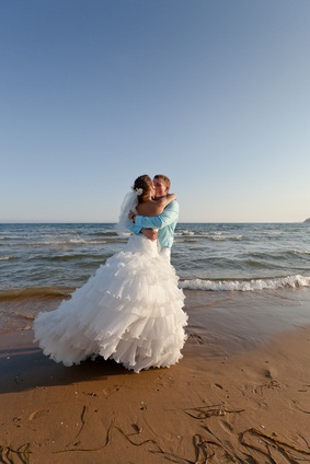 newlyweds hugging at the beach