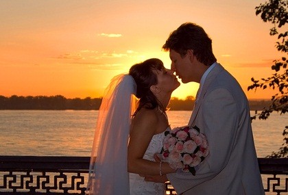newlyweds kissing as sun sets
