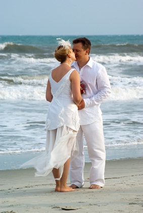 newlyweds kissing by the ocean